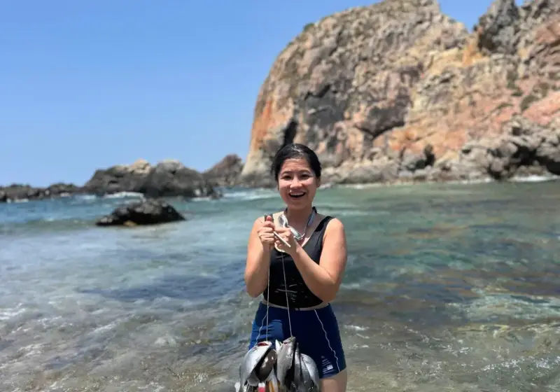 A guest wading in the shallows holding a string of freshly caught fish