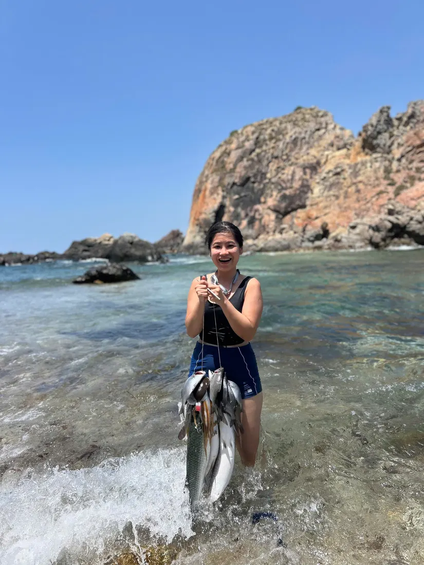 A guest wading in the shallows holding a string of freshly caught fish