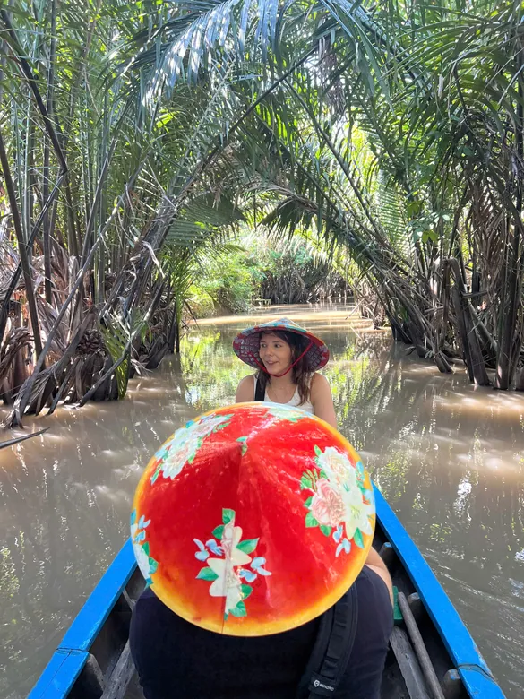 Rowing boat gliding beneath a canopy of water coconut palms, Mekong Delta