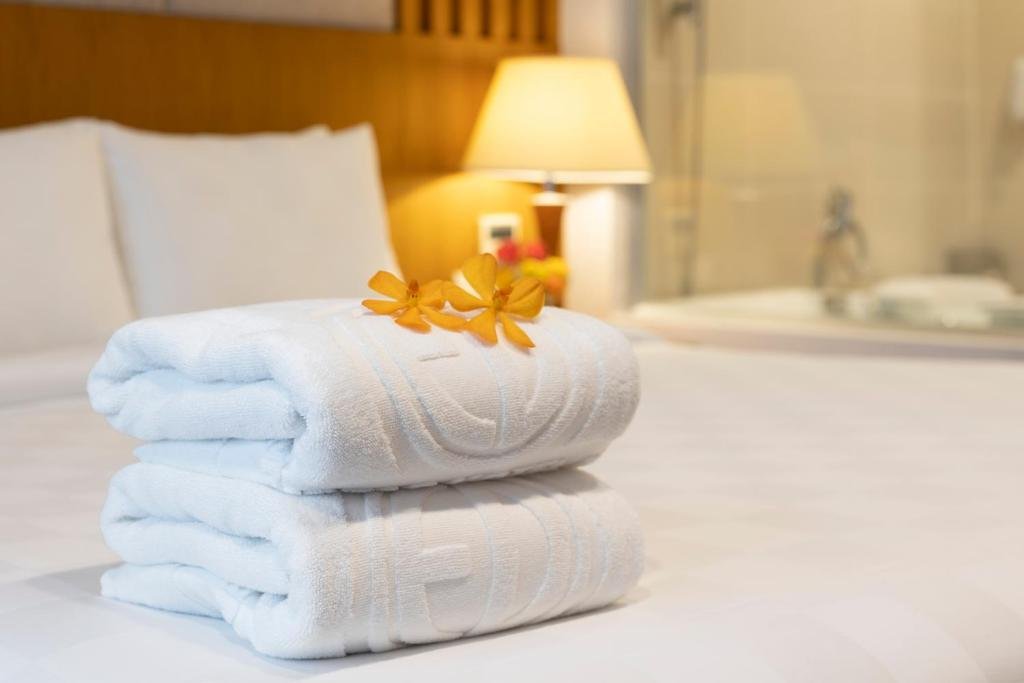 Two rolled white towels with yellow orchids on the bed, a lamp glowing behind