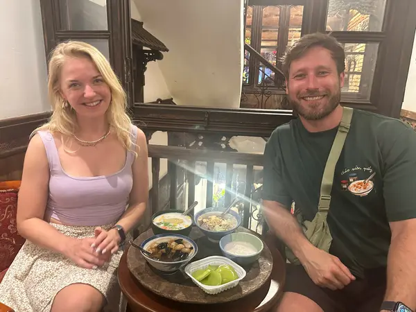 Two guests sitting over bowls of che at a wooden table in an Old Quarter cafe