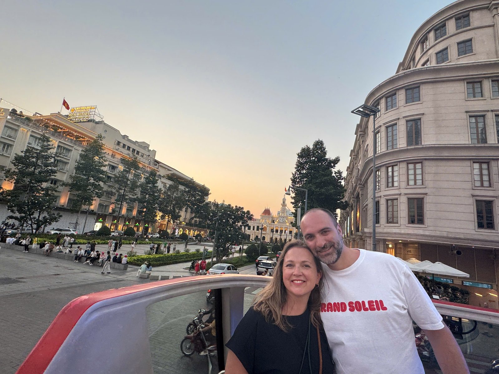 Guests on the top deck at dusk with Ho Chi Minh City Hall and the Rex Hotel behind them