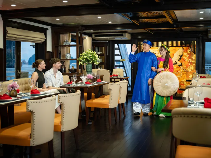A performer in a blue ao dai greeting guests at their table during the Heritage Footsteps cultural show in the restaurant