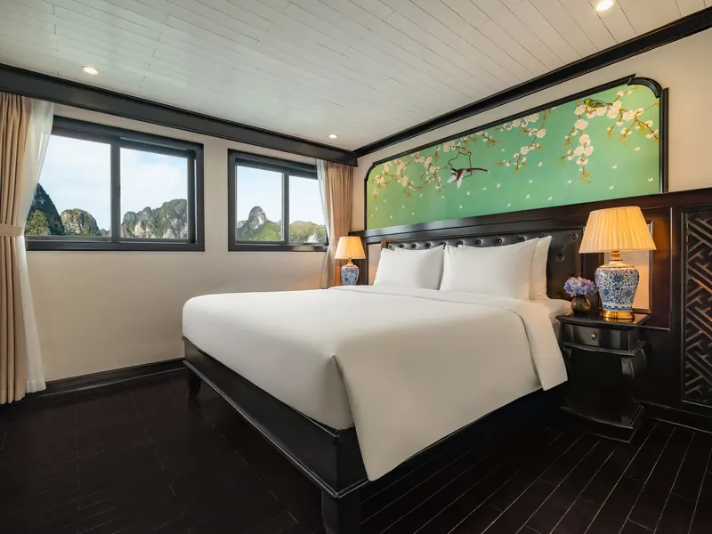 Deluxe Sea View cabin on deck 1: double bed, green hand-painted blossom headboard panel and a sea-view window looking onto the karsts