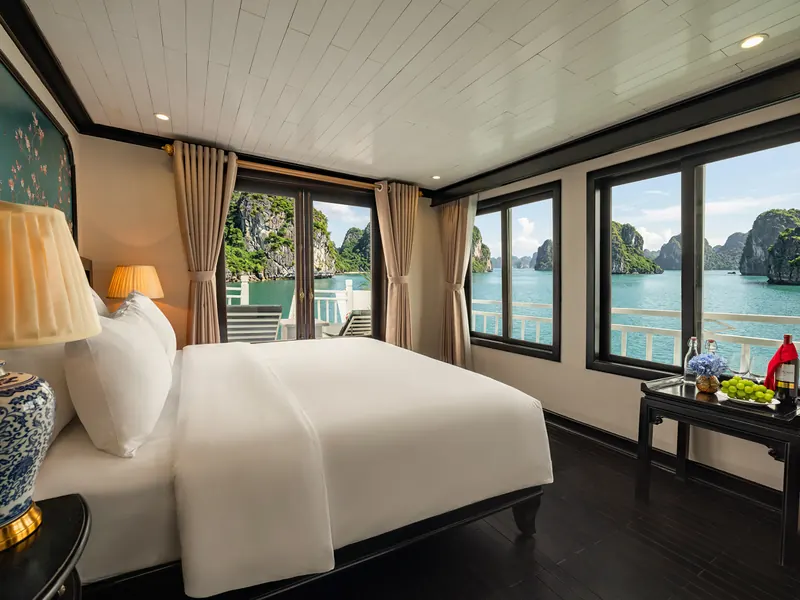 Premium Terrace cabin: corner room with windows on two sides looking out over Halong Bay and a private terrace beyond the glass