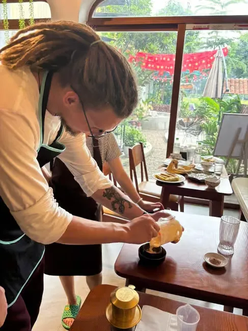 A guest pouring the whisked egg cream over black coffee