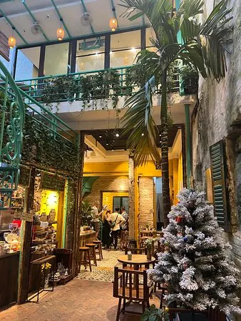 A leafy Hanoi cafe courtyard with balconies, palms and low wooden stools