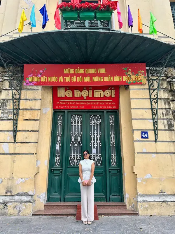 A yellow French-era facade with green shutters and a red banner in the Old Quarter