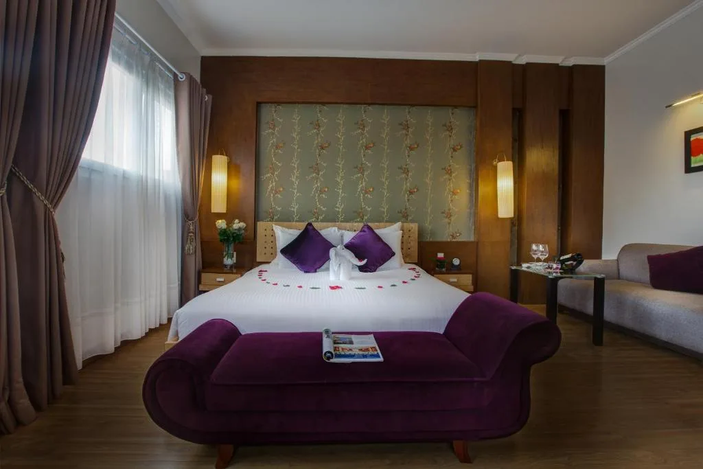 Executive Suite: a king bed under a painted floral panel, a purple chaise and a sofa by the window