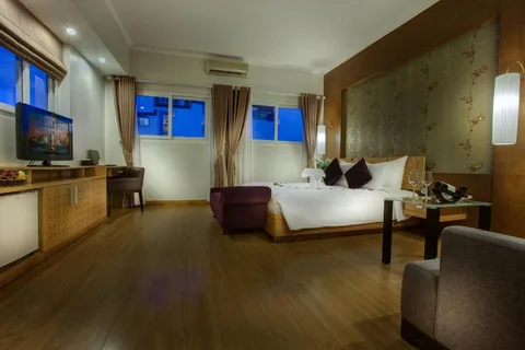 Executive Suite: the bedroom from the door, with the floral panel headboard, the purple chaise and windows at dusk