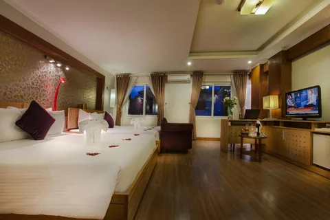 Family Suite: the two beds under a gold damask panel, with an armchair and windows at night