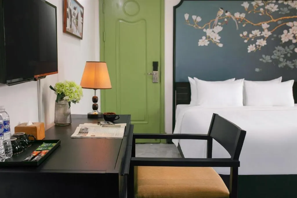 Writing desk with tea tray, lamp and flowers beside the bed